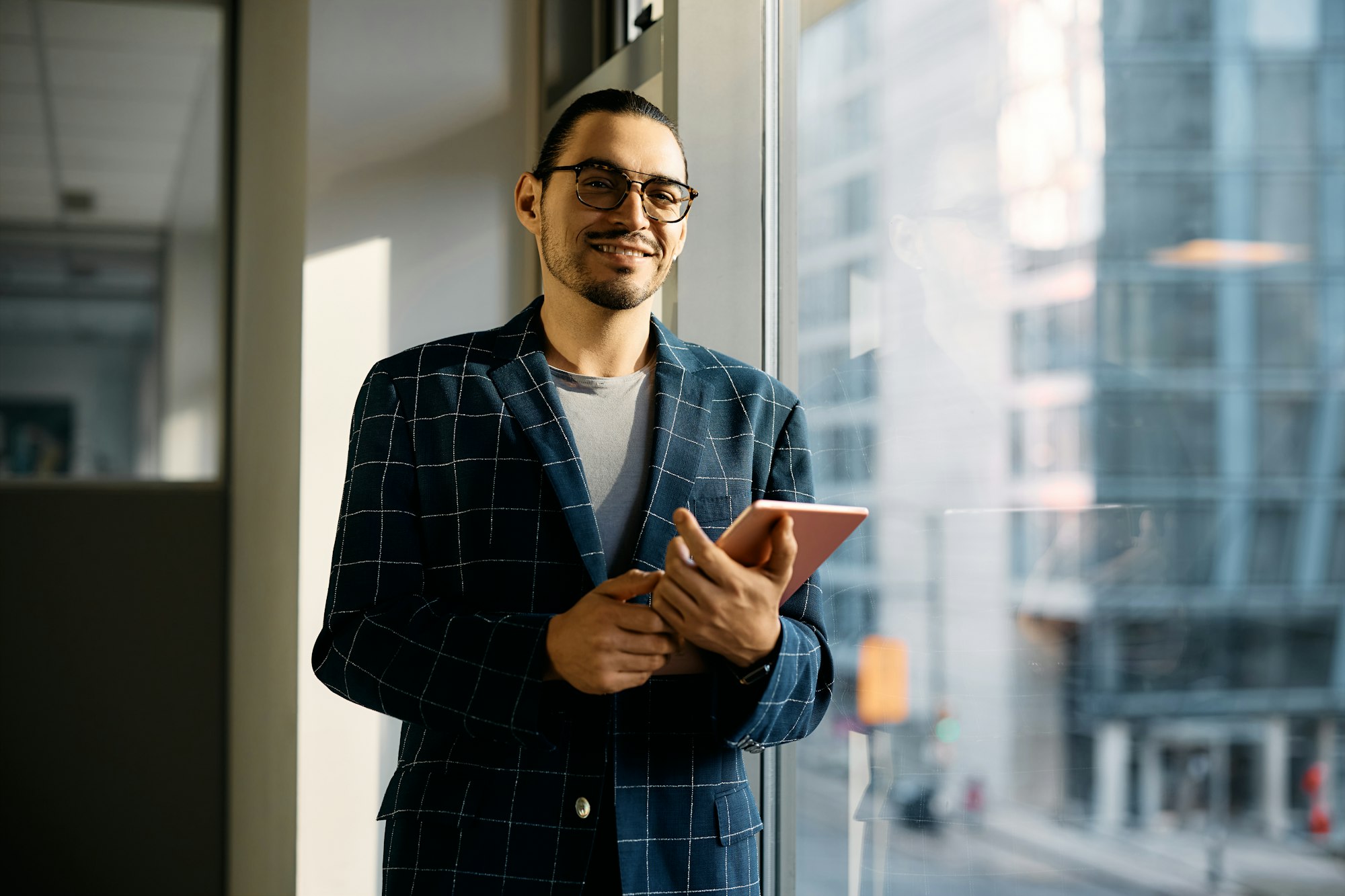 Portrait of Latin American businessman with touchpad in the office looking at camera.