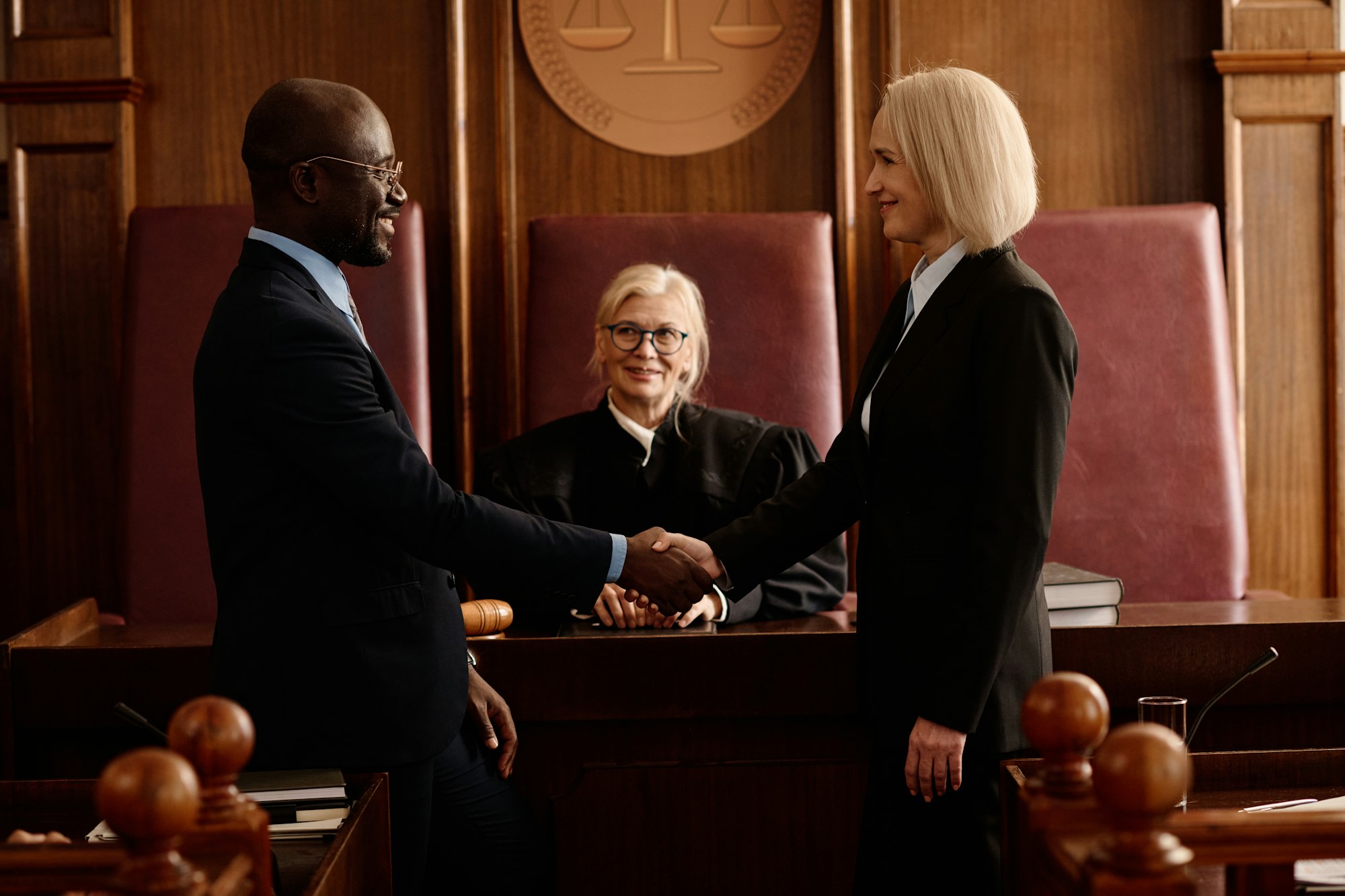 Side view of happy prosecutor and attorney shaking hands after making agreement